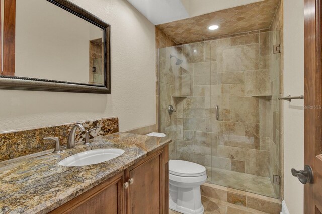 bathroom with toilet, a shower stall, and vanity