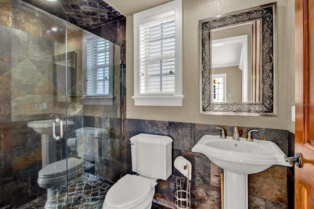 bathroom featuring a stall shower, a healthy amount of sunlight, tile walls, and toilet