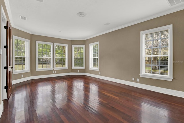 spare room featuring hardwood / wood-style floors, plenty of natural light, visible vents, and baseboards