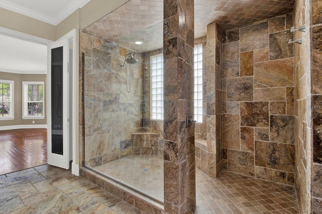 bathroom with a stall shower, stone tile flooring, crown molding, and baseboards