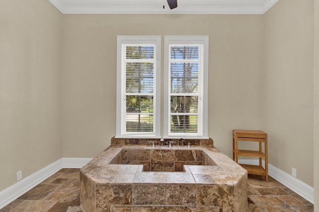 bathroom featuring ornamental molding, a bathtub, stone tile flooring, and baseboards