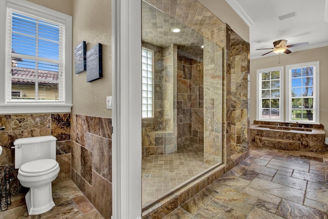 bathroom with toilet, tiled shower, tile walls, and stone tile floors