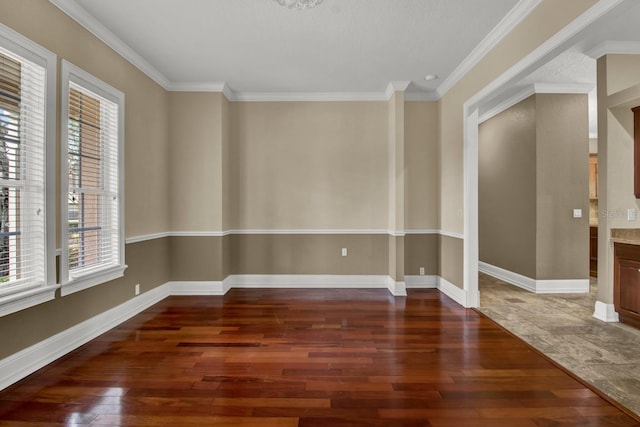 spare room with ornamental molding, wood-type flooring, and baseboards