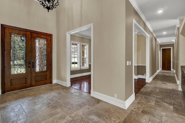 entryway with ornamental molding, stone tile flooring, and baseboards