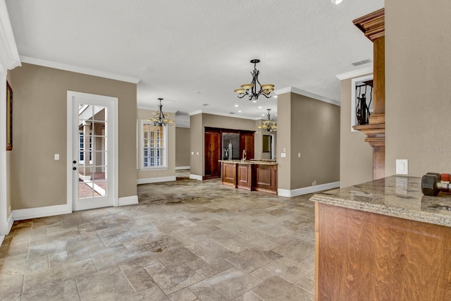 interior space featuring baseboards, visible vents, stone finish floor, ornamental molding, and a chandelier