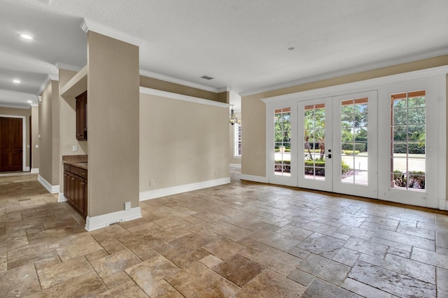 empty room featuring baseboards, french doors, crown molding, and stone tile floors