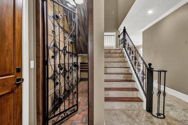 stairs with a textured wall, ornamental molding, recessed lighting, and baseboards