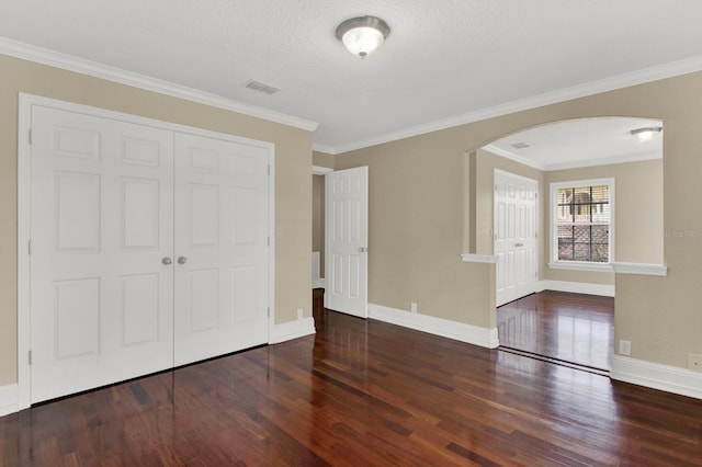 interior space with arched walkways, a closet, visible vents, wood finished floors, and baseboards