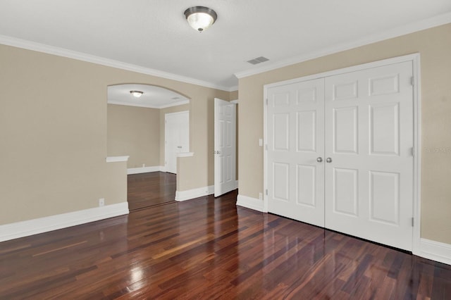 unfurnished bedroom featuring baseboards, visible vents, arched walkways, wood finished floors, and a closet