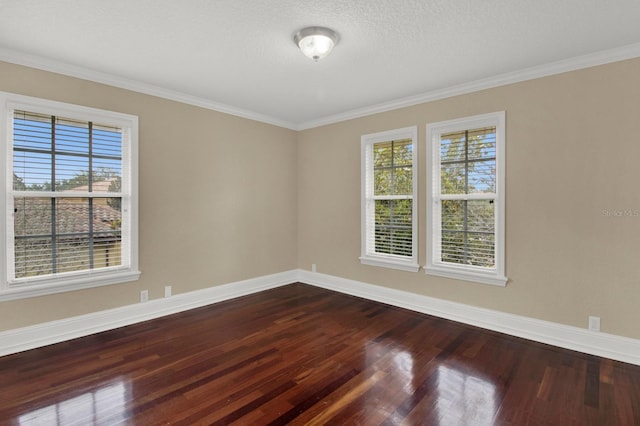 spare room featuring ornamental molding, dark wood-type flooring, a textured ceiling, and baseboards