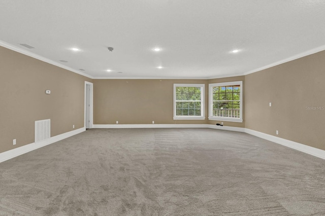 empty room with ornamental molding, carpet flooring, visible vents, and baseboards