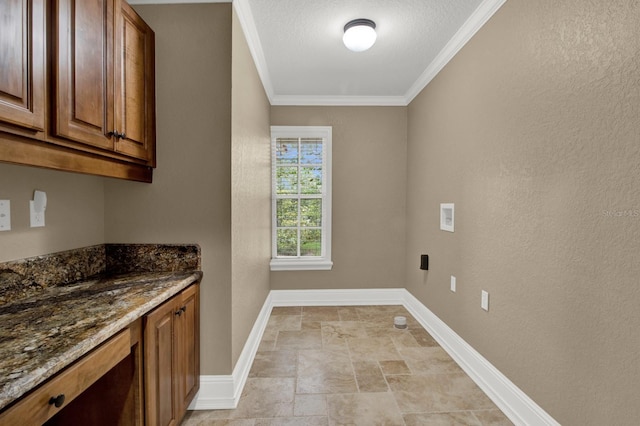 clothes washing area featuring cabinet space, baseboards, washer hookup, and crown molding