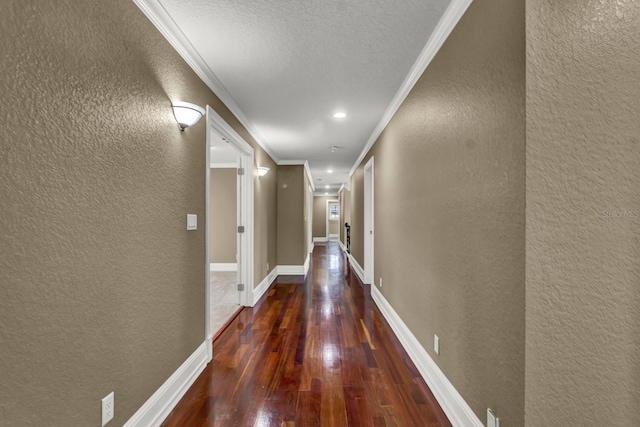 corridor with crown molding, wood-type flooring, a textured wall, and baseboards