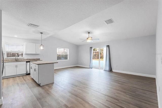 kitchen with visible vents, white cabinets, light wood-style flooring, a kitchen island, and open floor plan