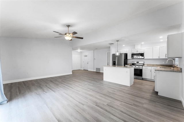 kitchen featuring visible vents, a kitchen island, open floor plan, stainless steel appliances, and a sink