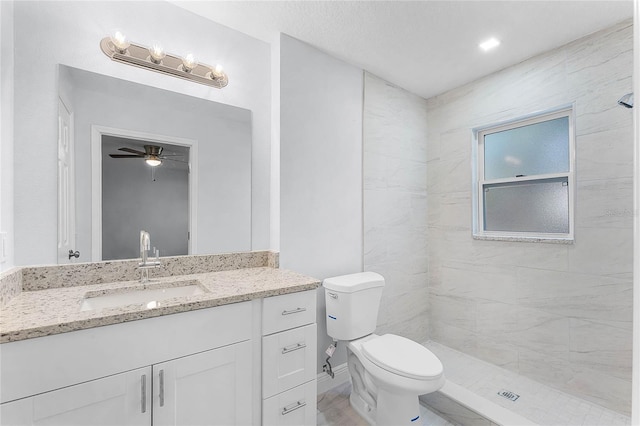 full bathroom with a tile shower, vanity, and toilet