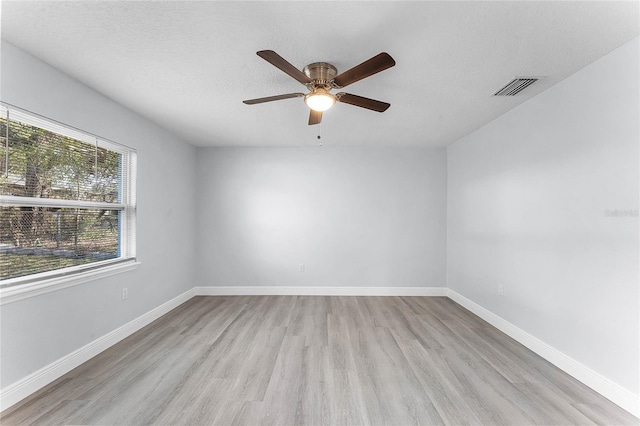 unfurnished room featuring baseboards, visible vents, ceiling fan, a textured ceiling, and light wood-type flooring