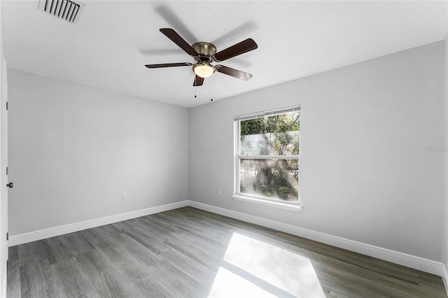 empty room featuring wood finished floors, visible vents, and baseboards