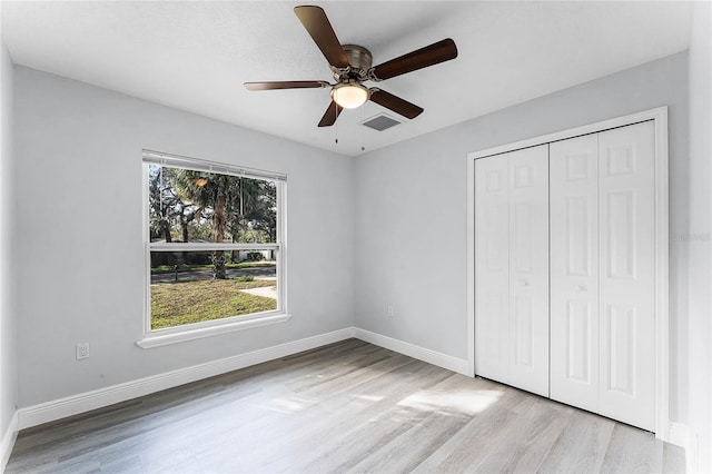 unfurnished bedroom with baseboards, visible vents, a ceiling fan, wood finished floors, and a closet