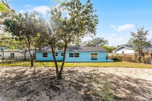 ranch-style home featuring fence and a front lawn