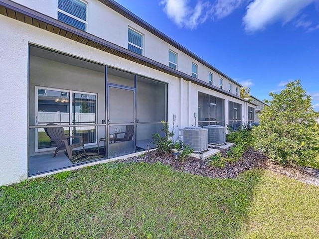 back of property featuring a sunroom, central AC, and stucco siding