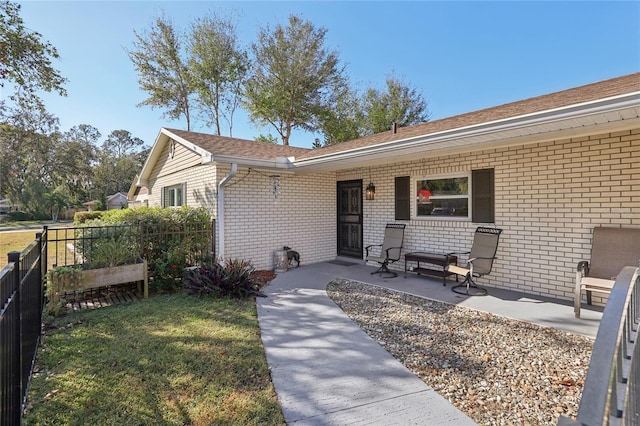 view of front of home featuring brick siding, a front lawn, a patio area, and fence