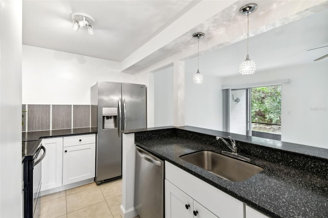 kitchen featuring white cabinets, appliances with stainless steel finishes, dark stone countertops, pendant lighting, and a sink