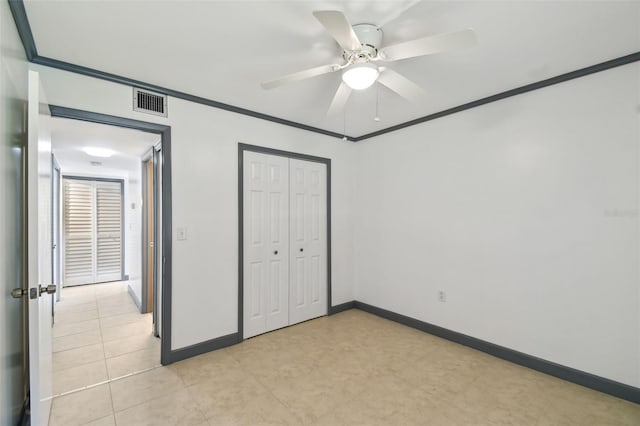 unfurnished bedroom featuring a ceiling fan, visible vents, baseboards, ornamental molding, and a closet