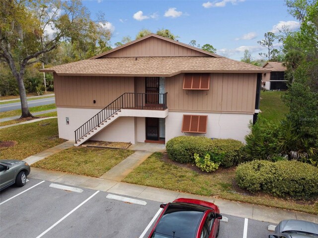 view of property with stairs and uncovered parking