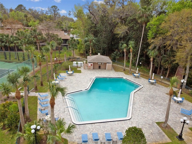 pool with an outbuilding, a patio, and fence