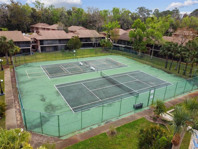 view of tennis court featuring a yard and fence