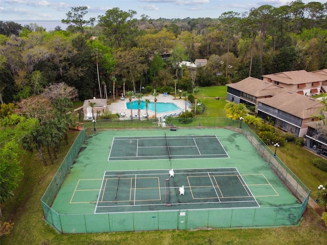view of sport court featuring fence and a view of trees