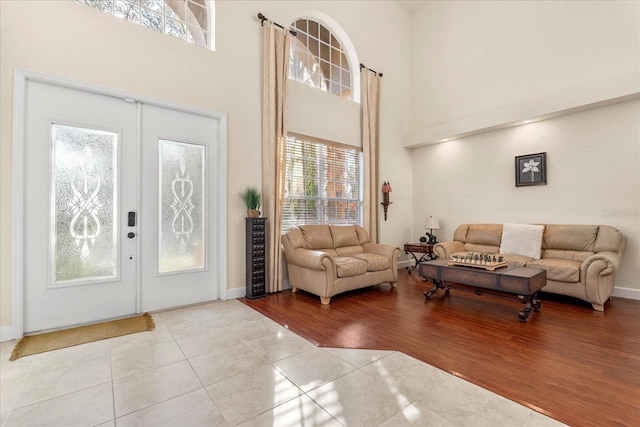 entryway with french doors, wood finished floors, a towering ceiling, and baseboards