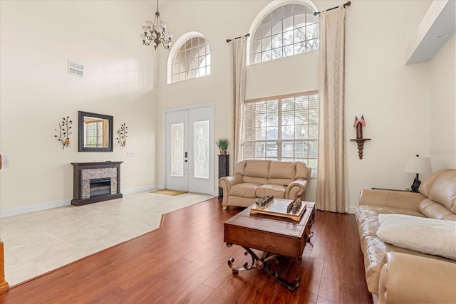 living room featuring a notable chandelier, a fireplace, wood finished floors, visible vents, and baseboards