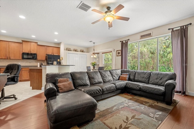 living area featuring light wood-style flooring, recessed lighting, visible vents, and a ceiling fan