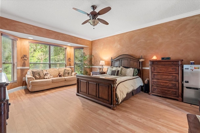 bedroom featuring light wood finished floors, baseboards, a ceiling fan, freestanding refrigerator, and crown molding