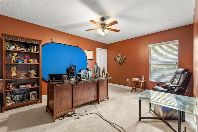 office space with light carpet, ceiling fan, baseboards, and a textured ceiling