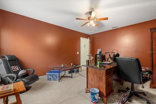 office featuring visible vents, a textured wall, a ceiling fan, light carpet, and a textured ceiling