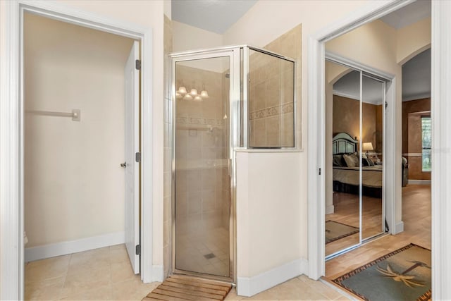 ensuite bathroom with a stall shower, tile patterned flooring, baseboards, and ensuite bathroom