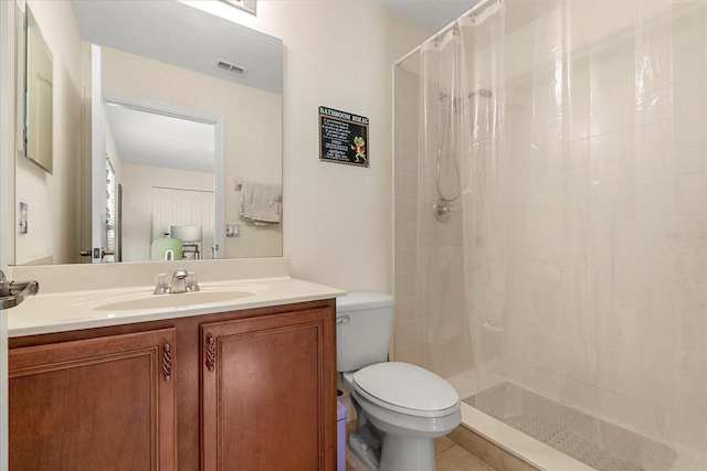 bathroom with visible vents, a tile shower, vanity, and toilet