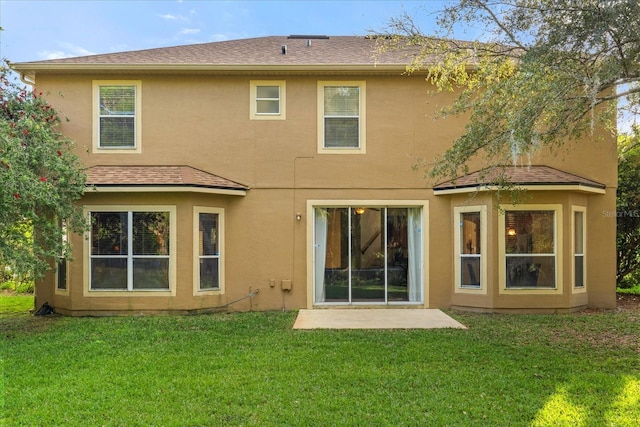 rear view of property with a shingled roof, a lawn, and stucco siding