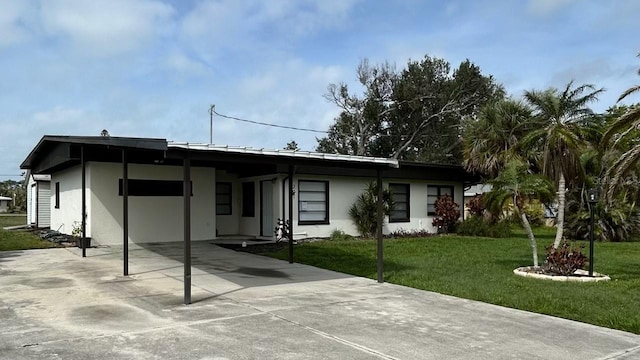 view of front of property featuring a front yard, a carport, driveway, and stucco siding