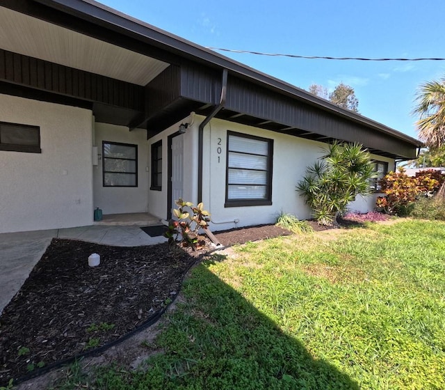 entrance to property with stucco siding and a lawn