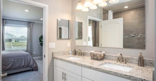 ensuite bathroom with ensuite bathroom, double vanity, a sink, and baseboards