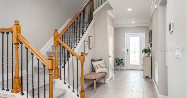 foyer featuring tile patterned floors, baseboards, crown molding, and recessed lighting