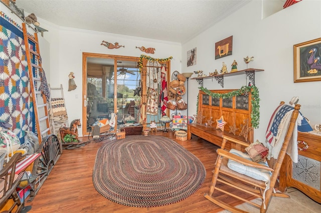 living area featuring a textured ceiling, wood finished floors, and crown molding