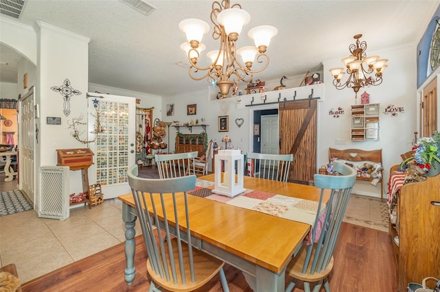 dining area featuring a chandelier, arched walkways, visible vents, and a barn door