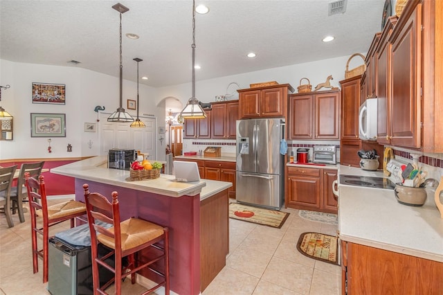 kitchen featuring white appliances, a kitchen island, light countertops, a kitchen bar, and light tile patterned flooring