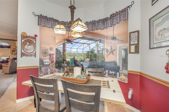 tiled dining space featuring a ceiling fan, a sunroom, and a high ceiling