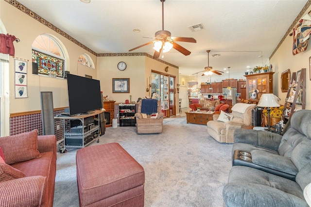 living room featuring light carpet, a wealth of natural light, visible vents, and a ceiling fan